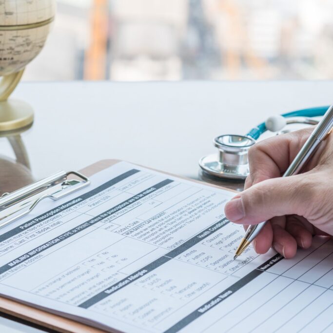 Doctor writing on medical health care record, patients discharge, or prescription form paperwork in hospital clinic
