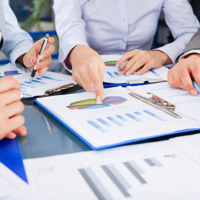 Business people team work group during conference discussing financial diagram, business charts, sitting, point finger at graph document